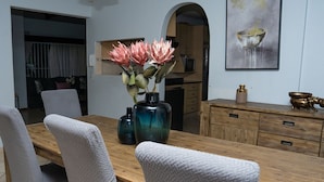 Un coin repas avec une table en bois, des chaises à revêtement gris et un vase rempli de fleurs.