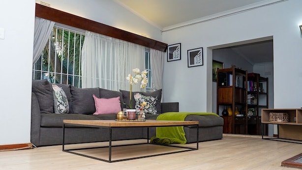 Un salon moderne avec un canapé gris, une table basse en bois et une bibliothèque.