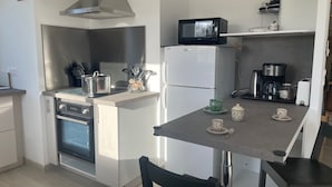 A compact kitchen with a built-in oven, microwave, and coffee maker. - Maison Neuve Livrée Début 2024 (Penmarc'h)
