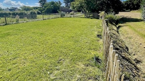 A grassy field with a wooden fence and trees in the background. - Maison Neuve Livrée Début 2024 (Penmarc'h)