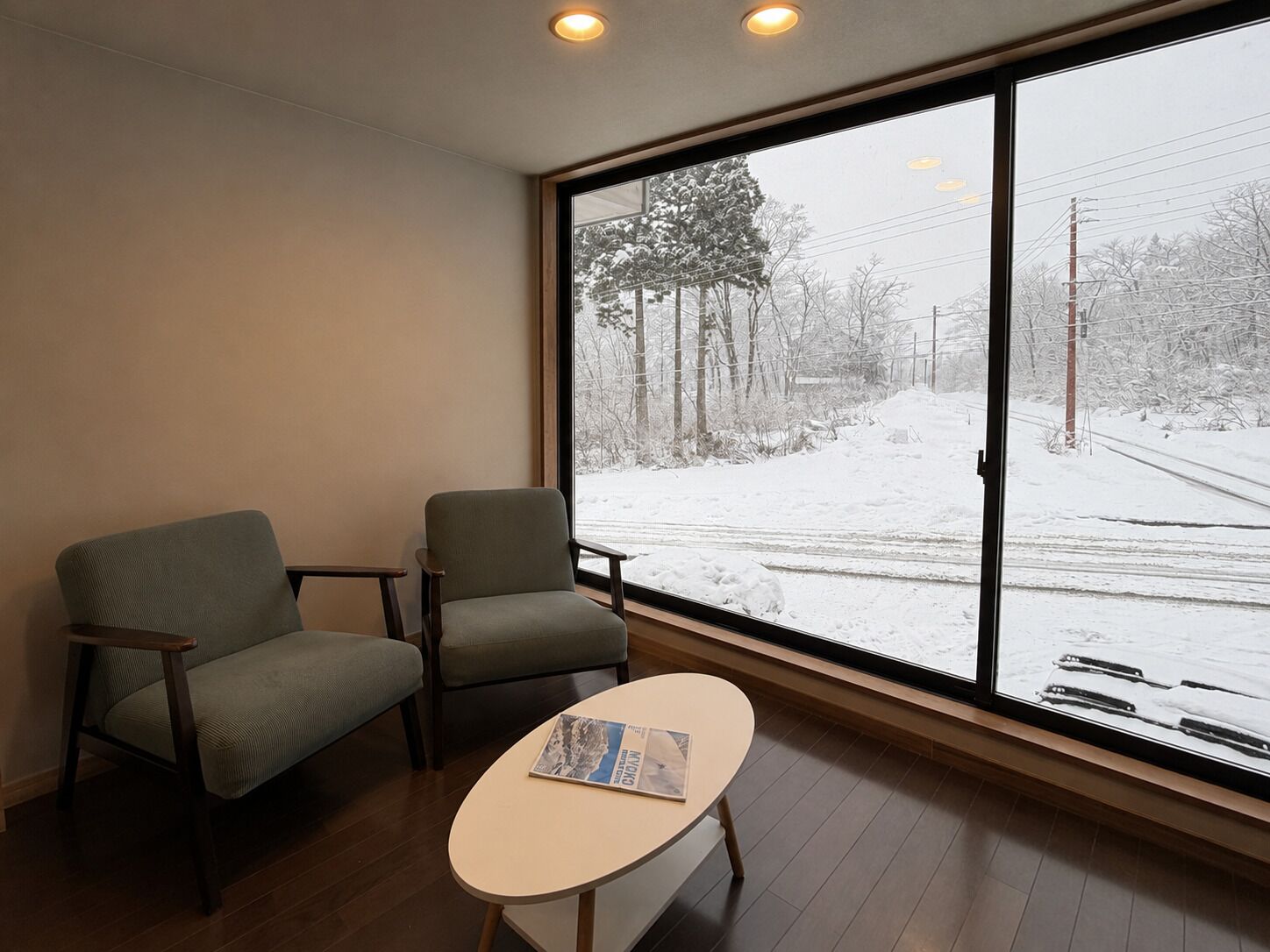 A room with two chairs and a small table, large windows with a view of a snowy landscape.