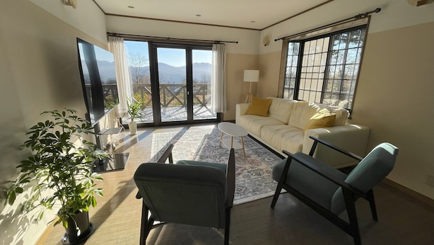 A spacious living room with a sofa, two chairs, a small table, and a potted plant. - Daiju Myoko (Myoko)