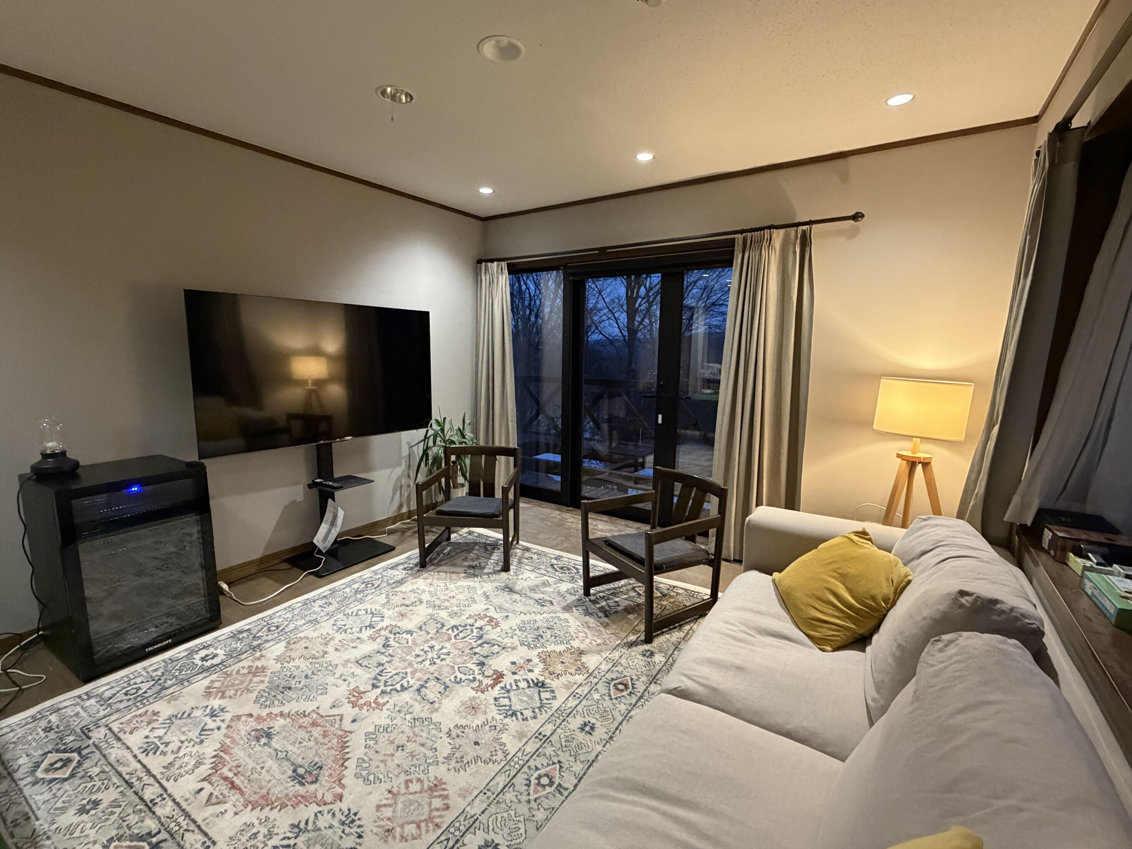 A living room with a flat-screen TV, a sofa, a coffee table, and a patterned rug.