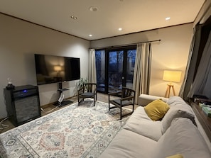 A living room with a flat-screen TV, a sofa, a coffee table, and a patterned rug. - Daiju Myoko (Myoko)