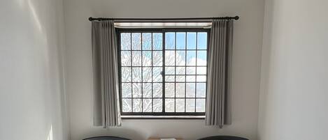 Una habitación con dos camas individuales, una ventana con cortinas, una mesita de noche y un radiador.