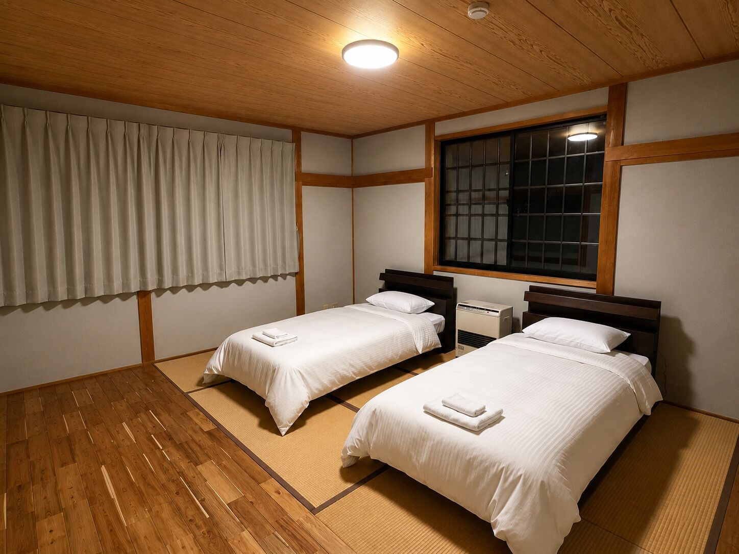 A room with two beds, a window, and a ceiling light.