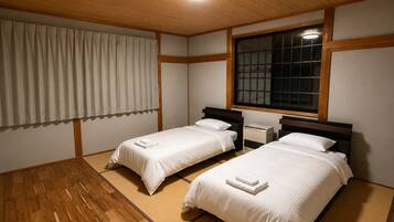 A room with two beds, a window, and a ceiling light.