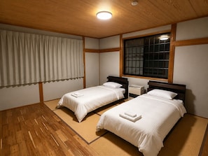 A room with two beds, a window, and a ceiling light. - Daiju Myoko (Myoko)