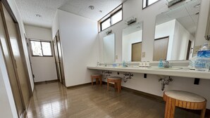 A clean, well-lit bathroom with a wooden floor, a large mirror, and a sink with multiple faucets. - Daiju Myoko (Myoko)