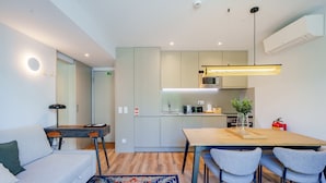 A modern kitchen with a wooden table and chairs, a microwave, and a coffee machine. - Feel Porto Firmeza Coworking Flat 4 1 (Porto)