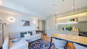 A modern living room with a sofa, a coffee table, and a dining area with chairs and a wooden table. - Feel Porto Firmeza Coworking Flat 4 1 (Porto)