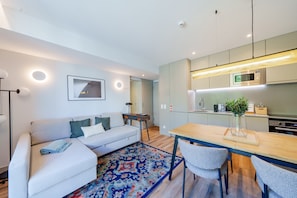 Uma sala de estar moderna com um sofá, uma mesa de centro e uma área de jantar com cadeiras e uma mesa de madeira.