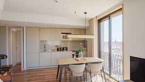 A modern kitchen with a dining area, large windows, and a view of the city. - Feel Porto Firmeza Coworking Flat 3 3 (Porto)
