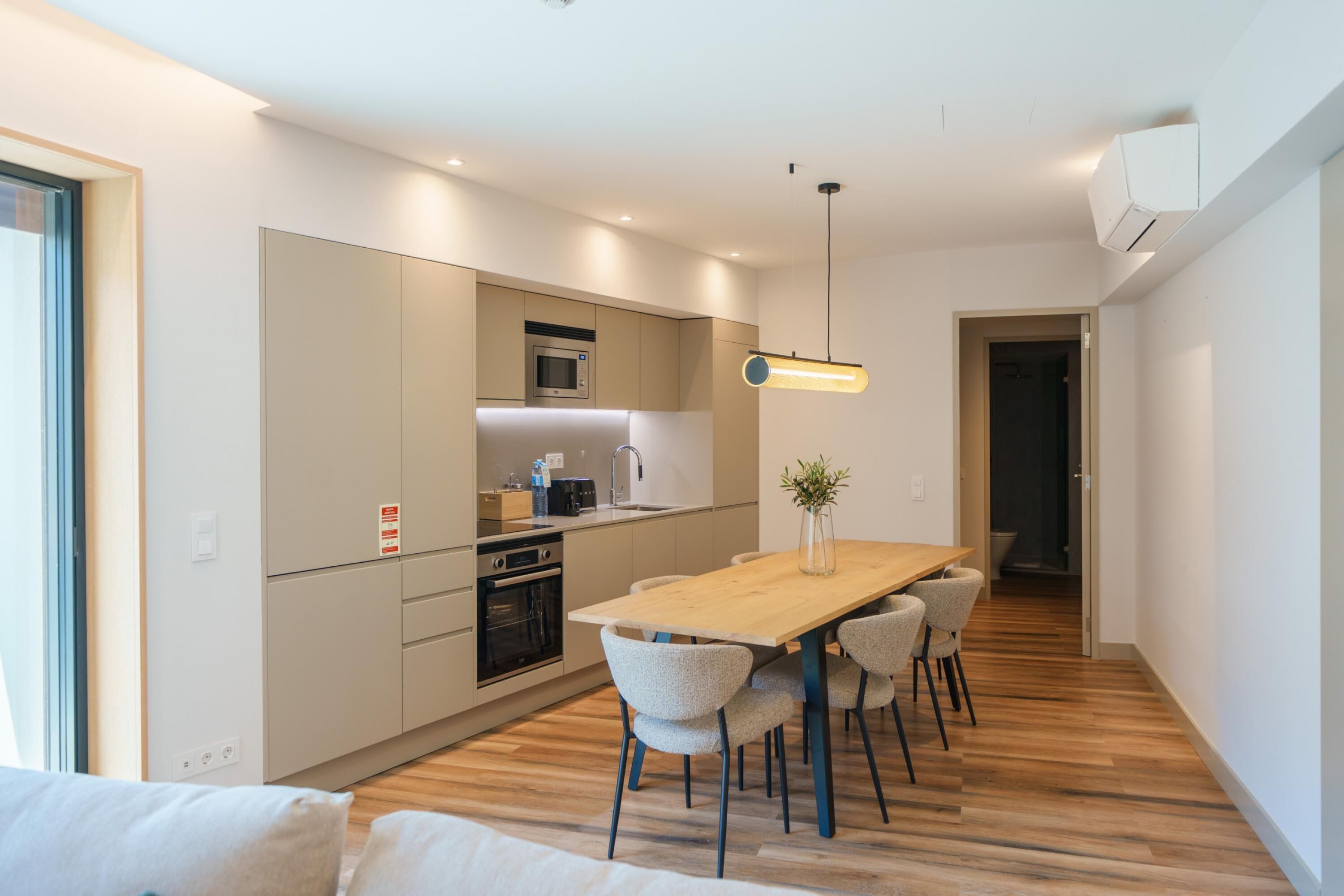 Een moderne keuken met een houten eettafel, inbouwapparatuur en een hanglamp.