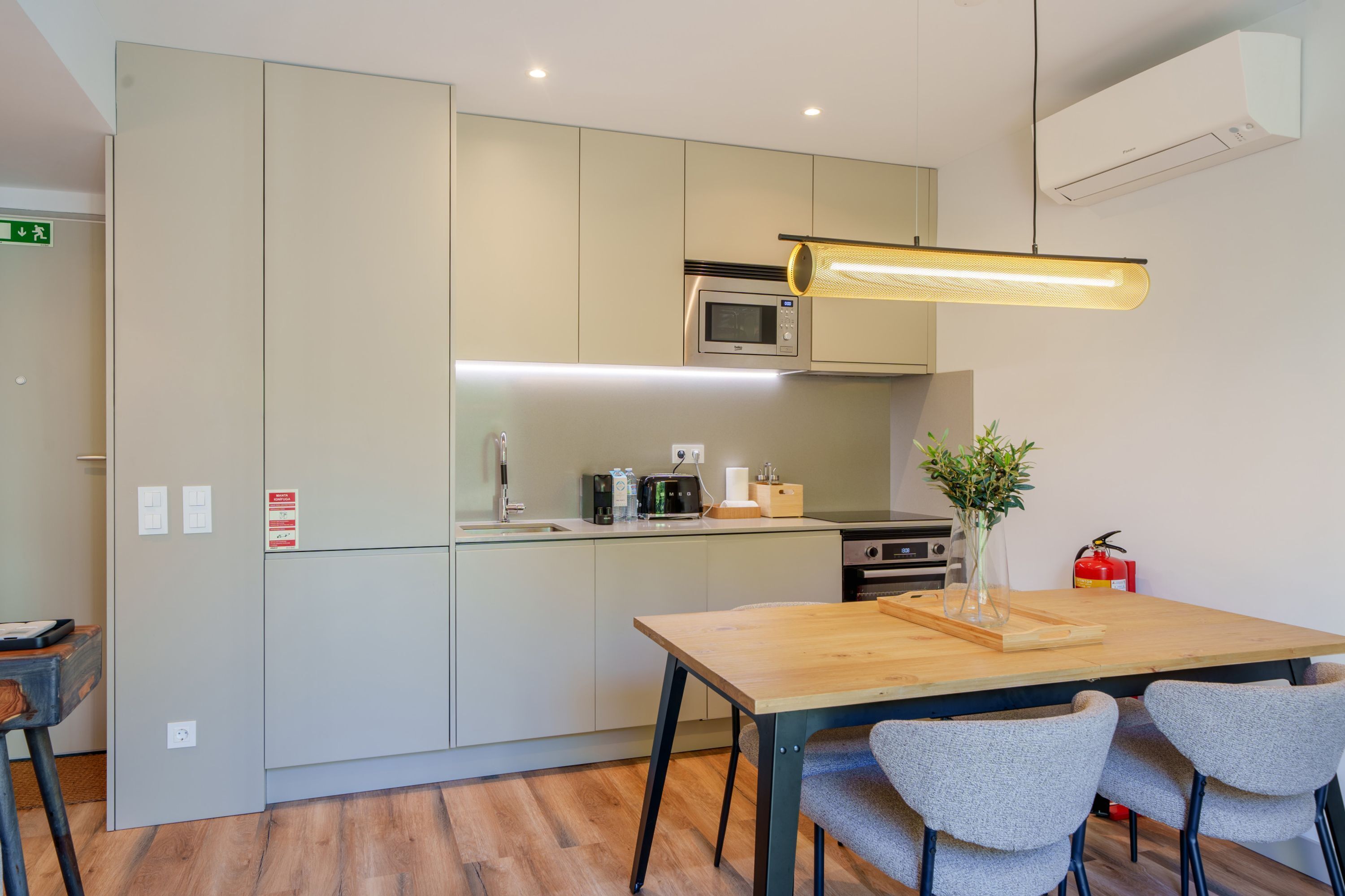 A modern kitchen with grey cabinets, a wooden table, and a microwave.