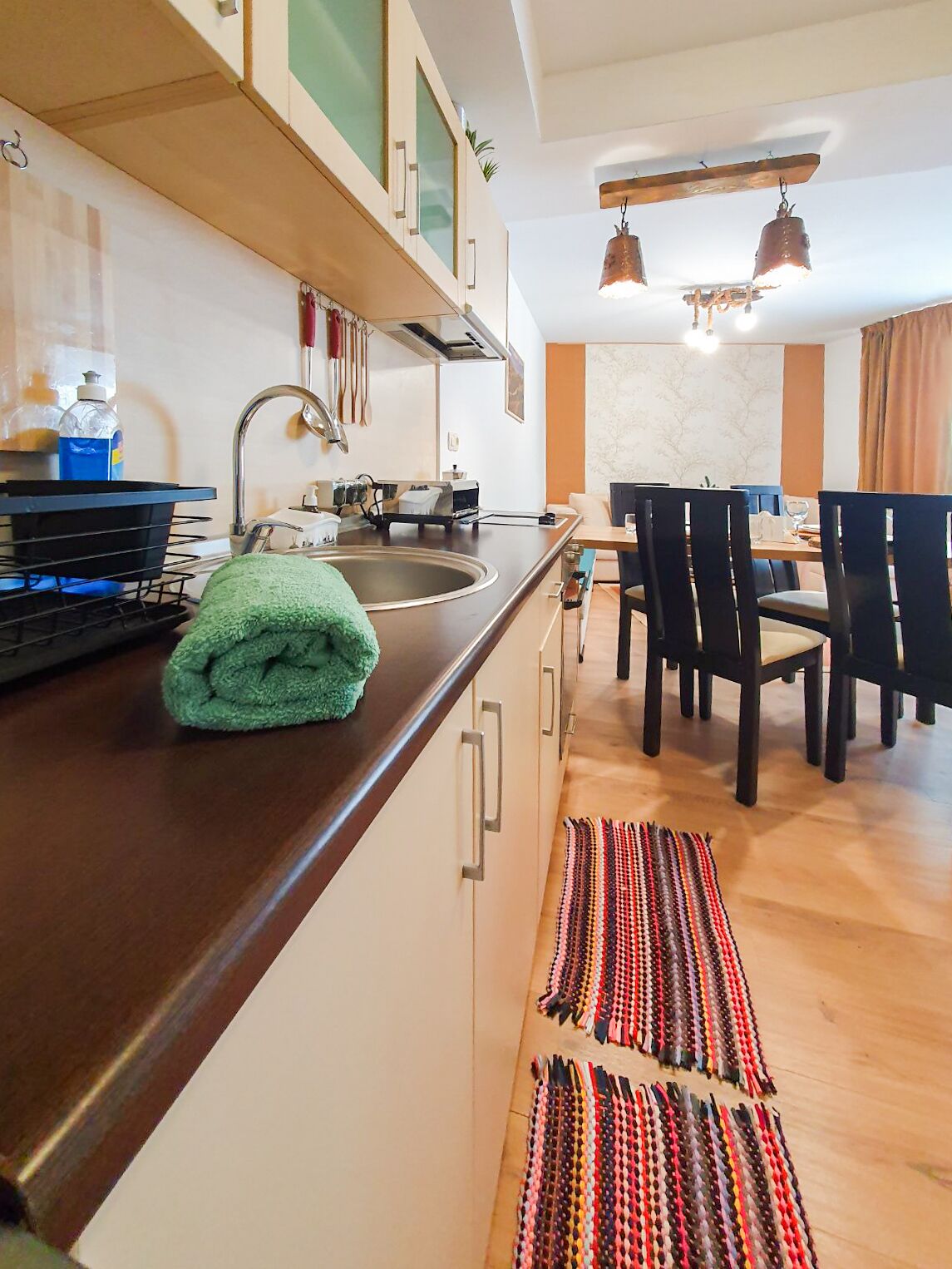 A modern kitchen with a built-in stove, a sink, and a dining area with a table and chairs.