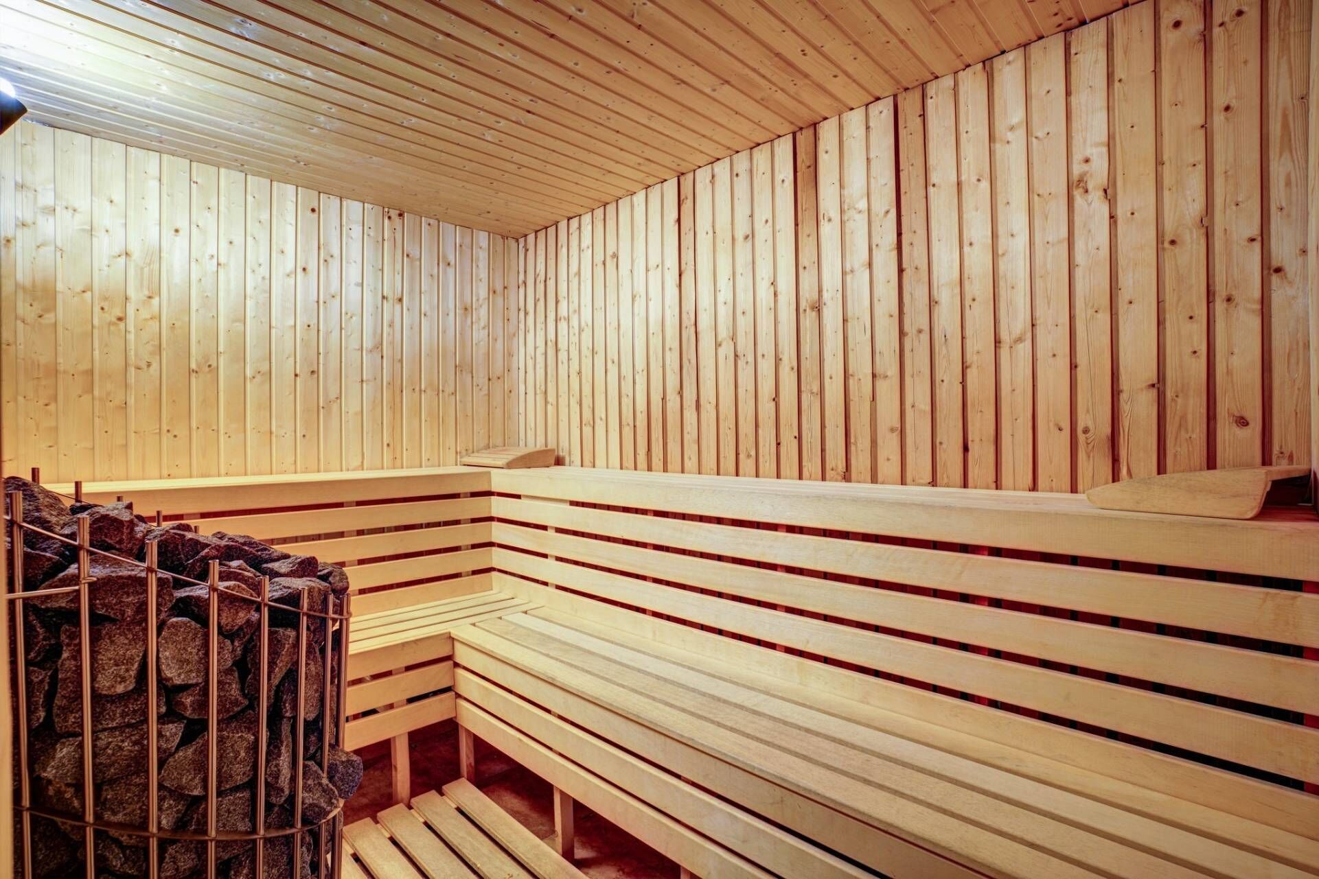 Un sauna avec des bancs en bois et un mur en pierre.