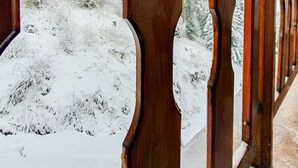 Un couloir en bois offrant une vue sur un paysage enneigé et des arbres couverts de neige.