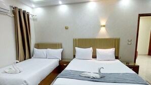 A hotel room with two beds, each with white linens and a wooden headboard. There is a wall-mounted light fixture above the beds and a small table with a lamp beside the beds. - Regent Pyramids View (Giza)