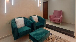A modern living room with a green sofa set, a pink armchair, and a patterned rug. - Regent Pyramids View (Giza)