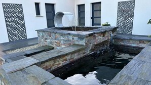 A stone water feature with a brick structure, surrounded by a stone deck and decorative panels.