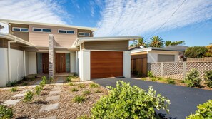A modern two-story house with a large garage, a stone staircase, and a landscaped driveway.