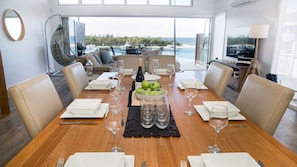 A dining area with a view of the sea, a table set with plates, glasses, and a bottle of wine. - Seaside Serenity Jervis Bay (Huskisson)