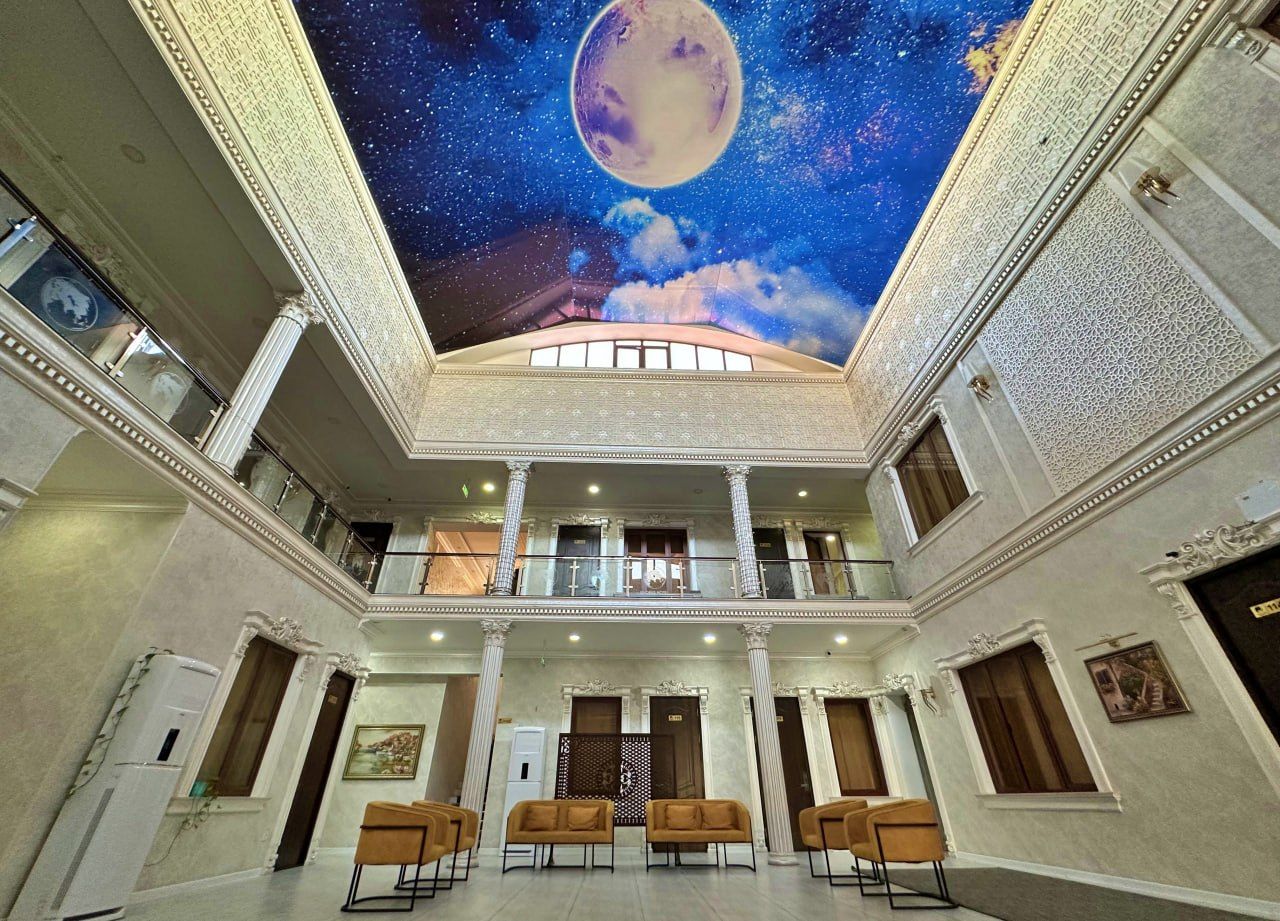 A spacious interior with a high ceiling, a central balcony, and a large mural of a moon and stars.