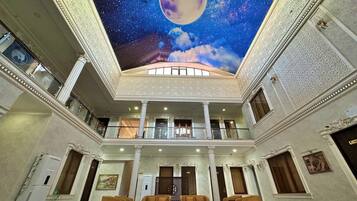 A spacious interior with a high ceiling, a central balcony, and a large mural of a moon and stars.