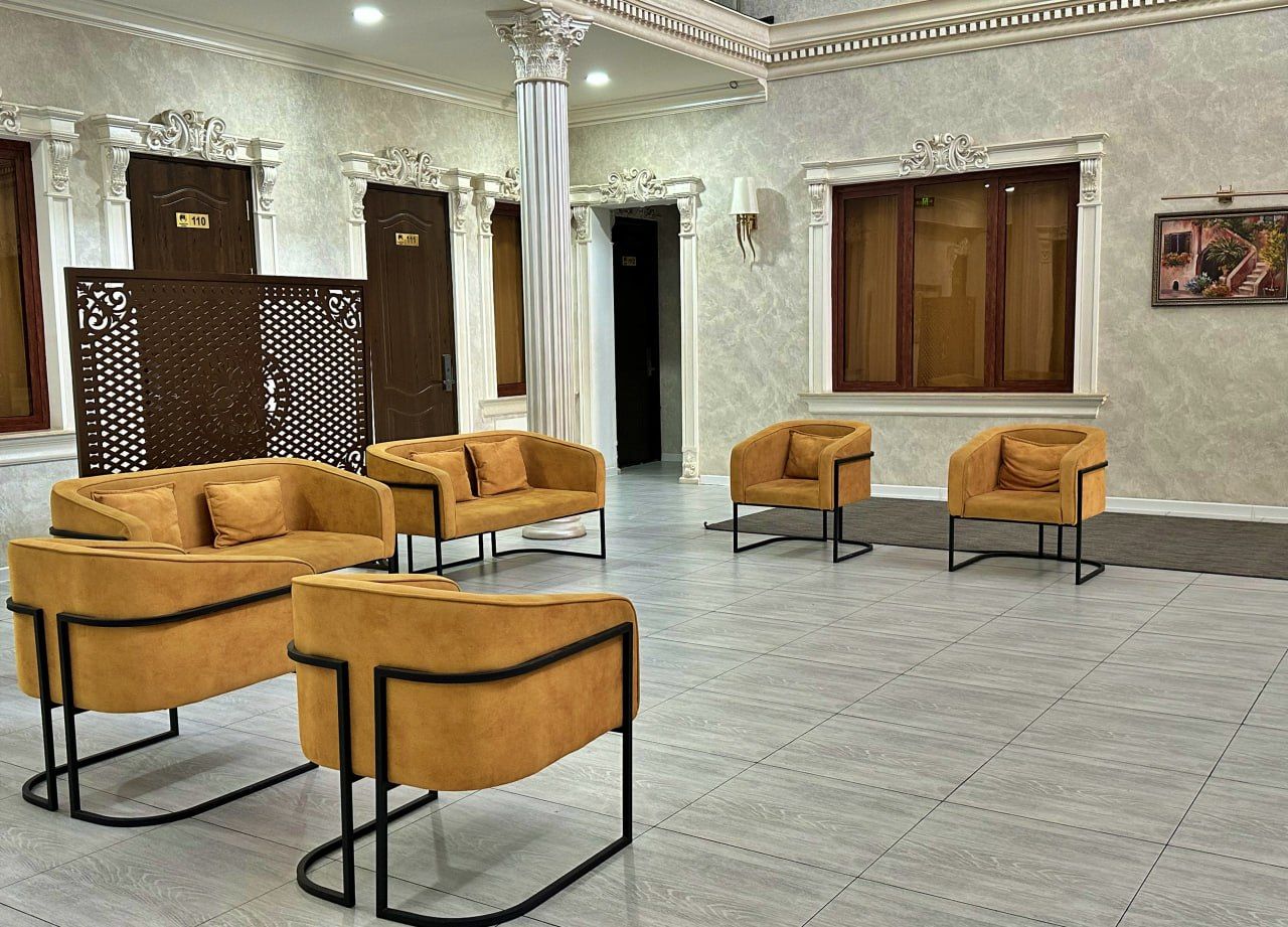 A lobby with a seating area featuring sofas and chairs, a reception desk, and a decorative wall with a framed picture.