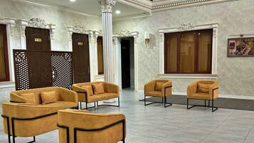 A lobby with a seating area featuring sofas and chairs, a reception desk, and a decorative wall with a framed picture.
