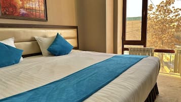 Une chambre d’hôtel avec un grand lit, une tête de lit, une fenêtre donnant sur des arbres et un tableau au mur.