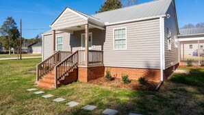 A two-story house with a front porch, a brick foundation, and a covered staircase.