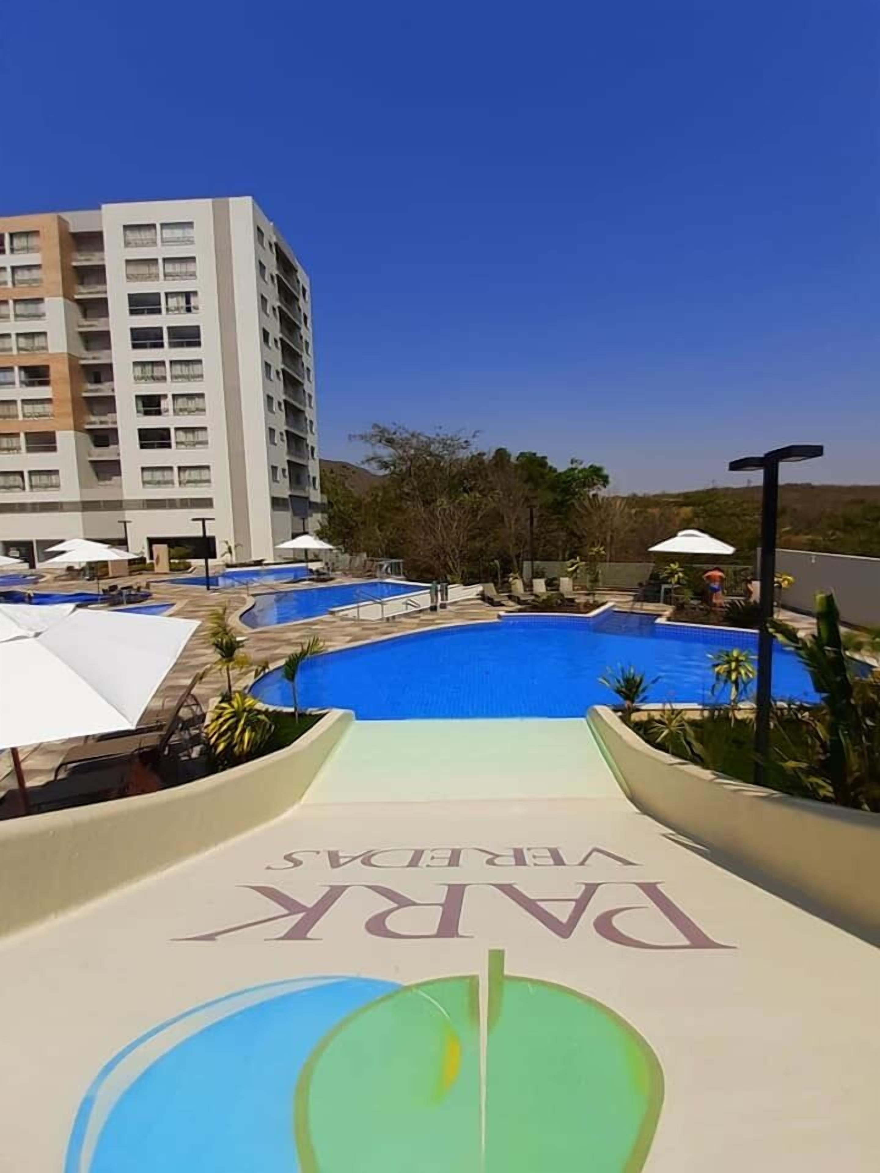 A pool area with multiple pools, umbrellas, and a building in the background.