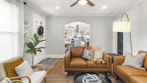 A modern living room with a brown leather sofa, a wooden chair, and a black coffee table. - Swamp Rabbit | Furman | Bikes | Pass | Fenced | EV (Greenville)