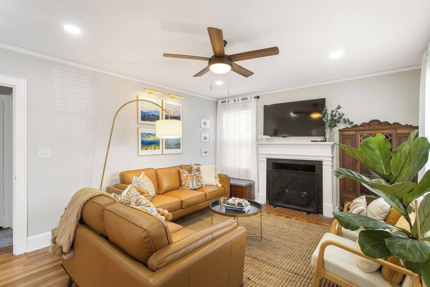 A living room with a sofa, coffee table, fireplace, and a ceiling fan.