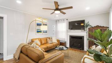 A living room with a sofa, coffee table, fireplace, and a ceiling fan.