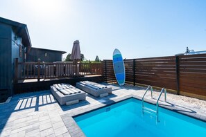 Ein Schwimmbecken mit Liegestühlen und einem Surfbrett.