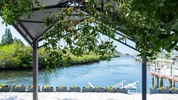 A riverside patio with outdoor seating, a covered area, and a view of the river. - Waterfront 2 bed/2 bath with direct Gulf access (Hudson)