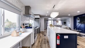 A modern kitchen with a central island, large windows, and a view of the outdoors. - Waterfront 2 bed/2 bath with direct Gulf access (Hudson)
