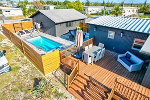 Eine Wohnterrasse mit Schwimmbad, Gartenmöbeln und einer überdachten Terrasse.