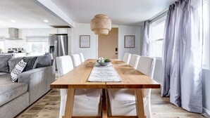 A modern living room with a wooden dining table, white chairs, a grey sofa, and a hanging light fixture. - Waterfront 2 bed/2 bath with direct Gulf access (Hudson)