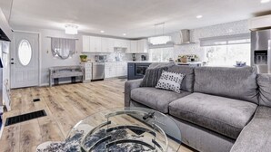 A modern kitchen with white cabinets, a grey sofa, and a glass coffee table. - Waterfront 2 bed/2 bath with direct Gulf access (Hudson)