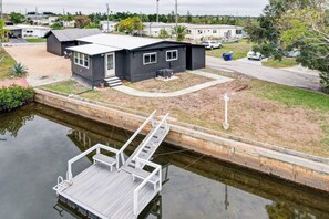Ein kleines, eingeschossiges Gebäude mit einem Steg, der in ruhiges Wasser führt.