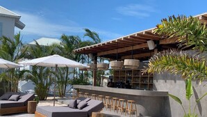 A poolside area with lounge chairs, a bar, and a covered seating area.
