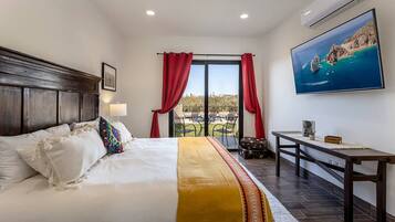 A hotel room with a large bed, a desk, and a view of the outdoors.