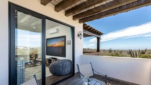 En balkon med fjernsyn, siddepladser og udsigt over ørkenen.