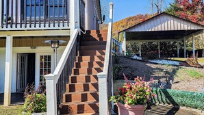 Ein zweistöckiges Haus mit einer Treppe zum Eingang, einer überdachten Veranda und einem Garten mit Blumentöpfen.