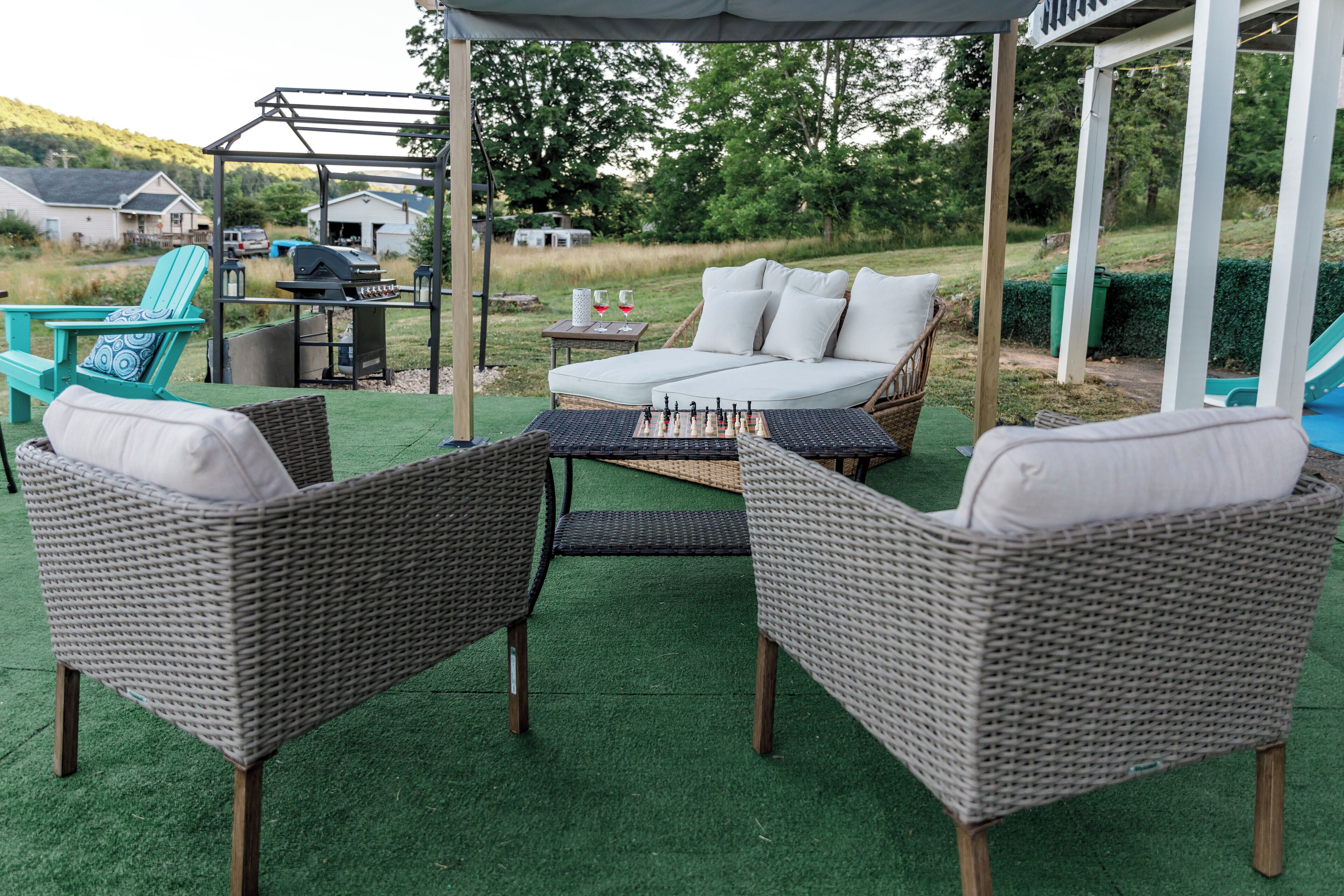 Une terrasse extérieure aménagée avec des meubles en osier, un barbecue et un espace salon abrité.