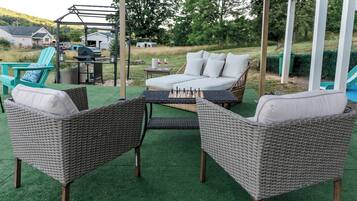 Une terrasse extérieure aménagée avec des meubles en osier, un barbecue et un espace salon abrité.